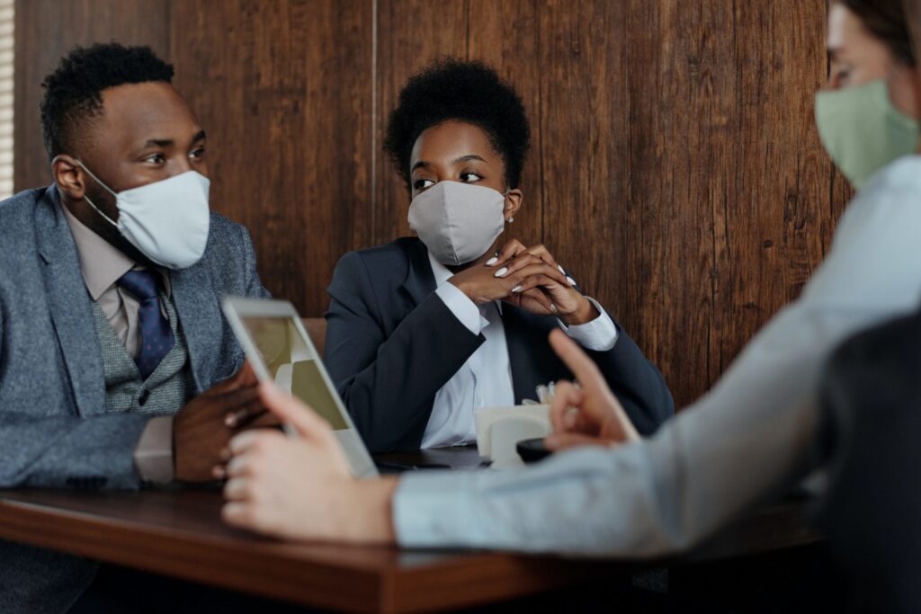 Picture of three people seated at a table with masks on