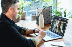 Leading in a digital world banner image - a man is sat at a desk on a video call