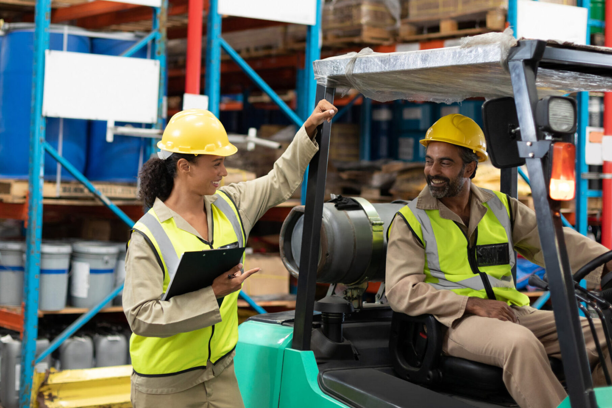 Happy male and female staff interacting with each other in warehouse. This is a freight transportation and distribution warehouse. Industrial and industrial workers concept