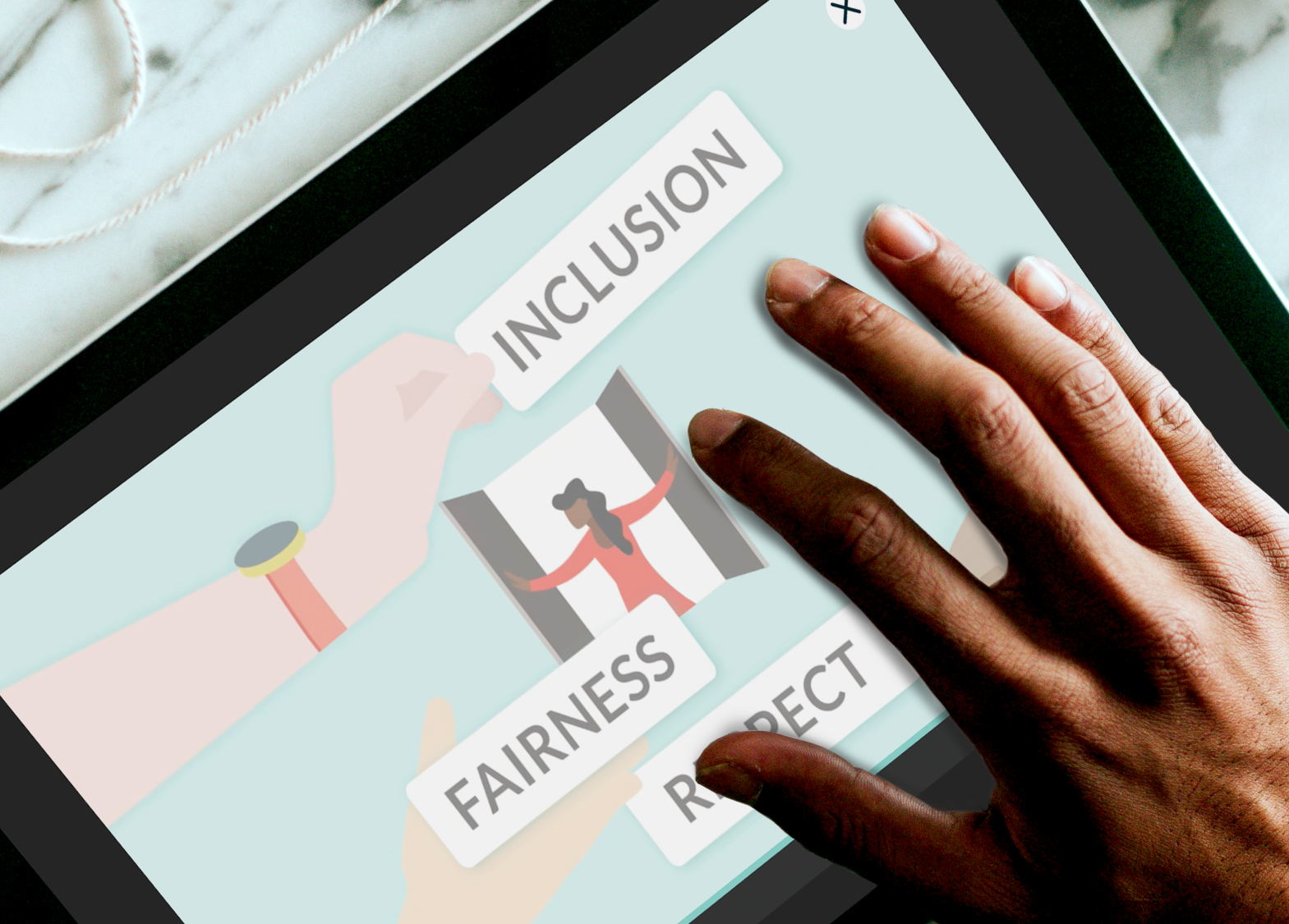 A hand touching a tablet screen that says 'Inclusion', 'Fairness' and 'Respect'